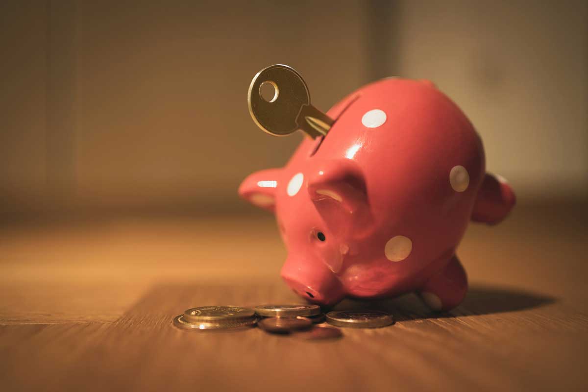 Piggy bank with key in money slot and coins on around it