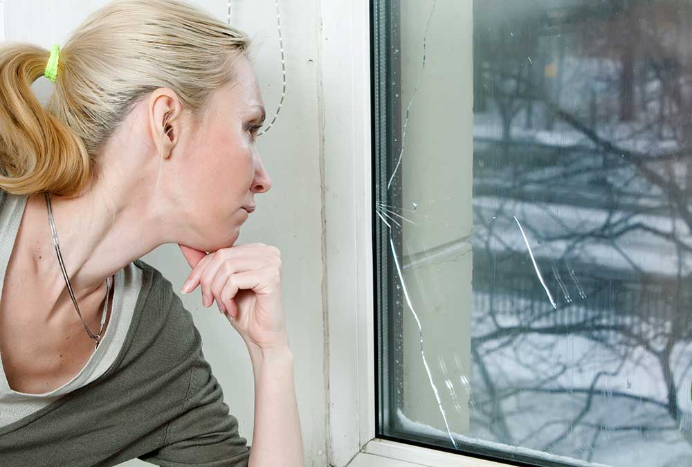 Broken Double Glazing Woman inspecting cracked window
